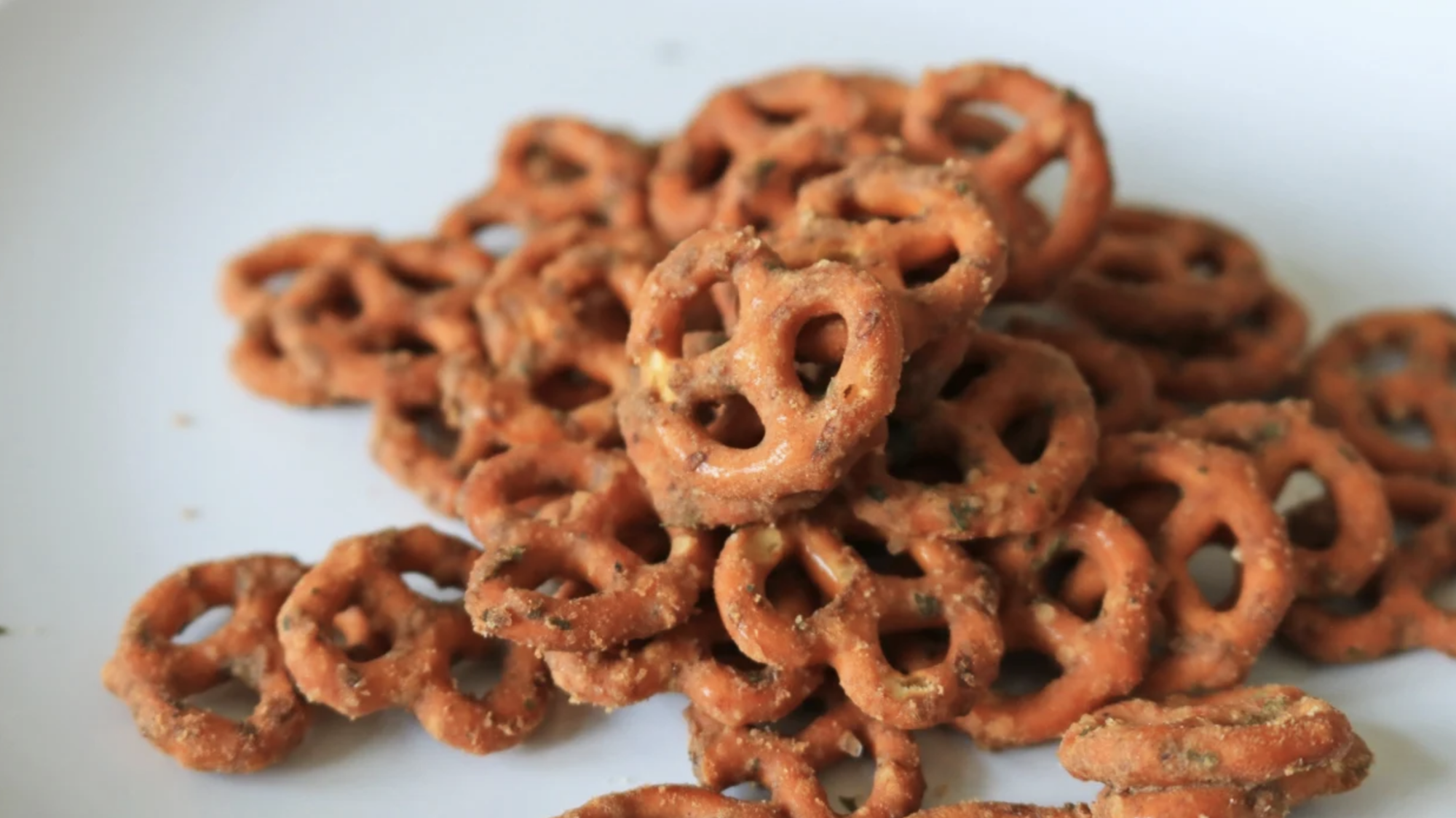 Seasoned pretzels piled up on a white plate.