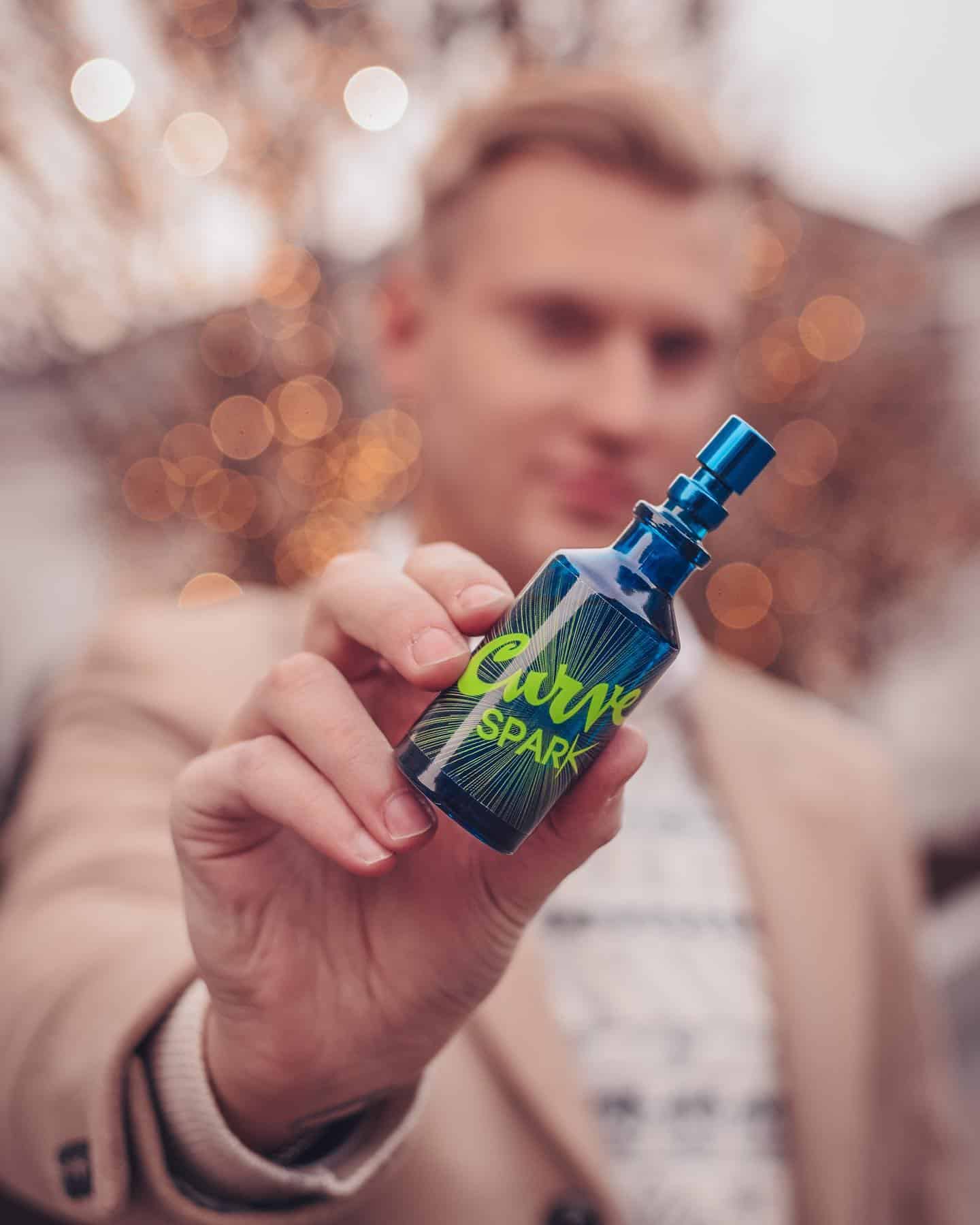 man holding a bottle of curve spark cologne